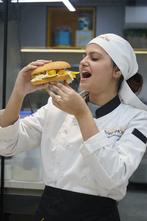 Person in a chef's outfit receiving a large sandwich from above