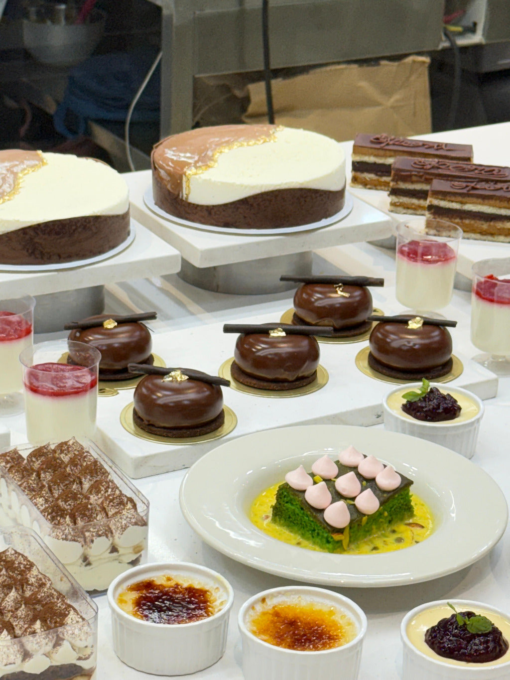 Display of various desserts including cakes and pastries on a white surface.
