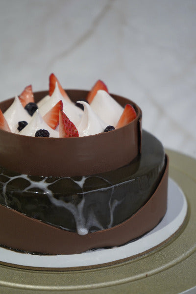 Close-up of a cake with berries and cream in a decorative mold.