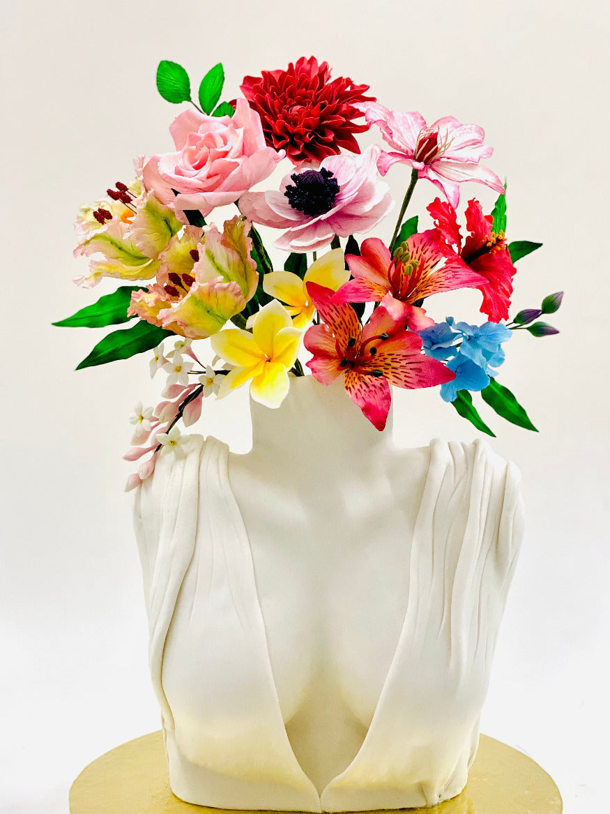 A decorative cake designed with a variety of colorful icing and flower decorations, presented in a vase.