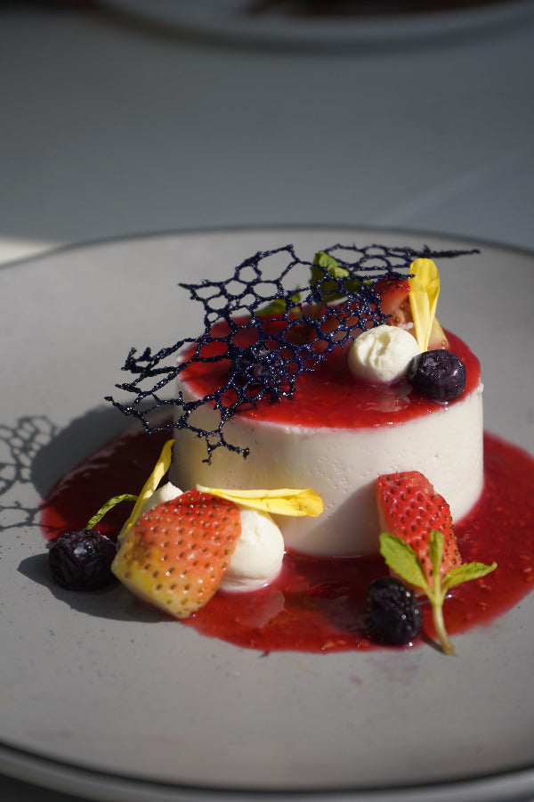 Delicate dessert with strawberries, cream, and blackberries on a white plate at 'La Bake Amore'.