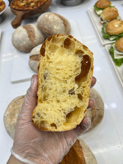 Hand holding a piece of bread with a white background featuring other food items.