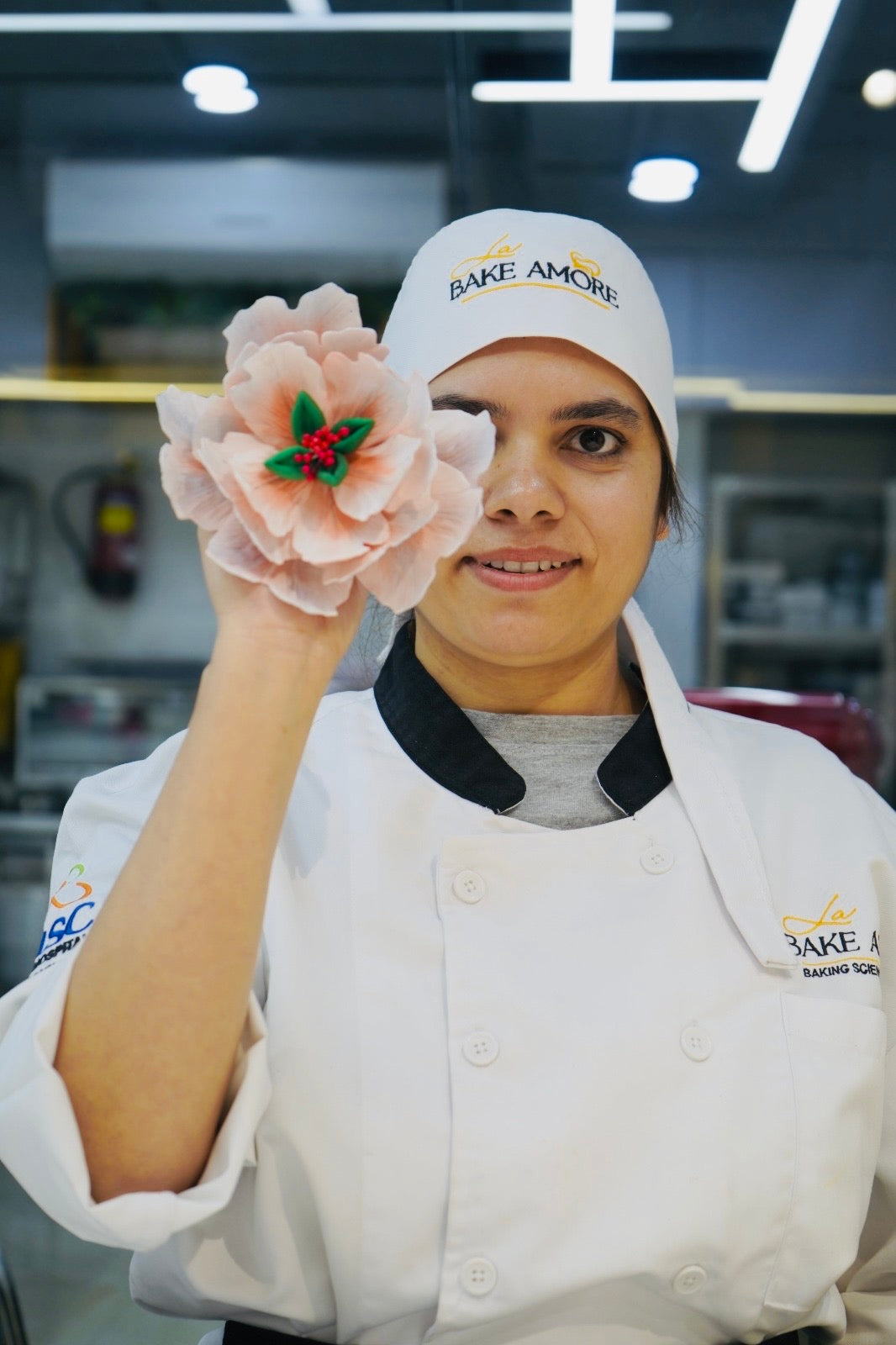 Person in a bakery uniform holding a decorated cake