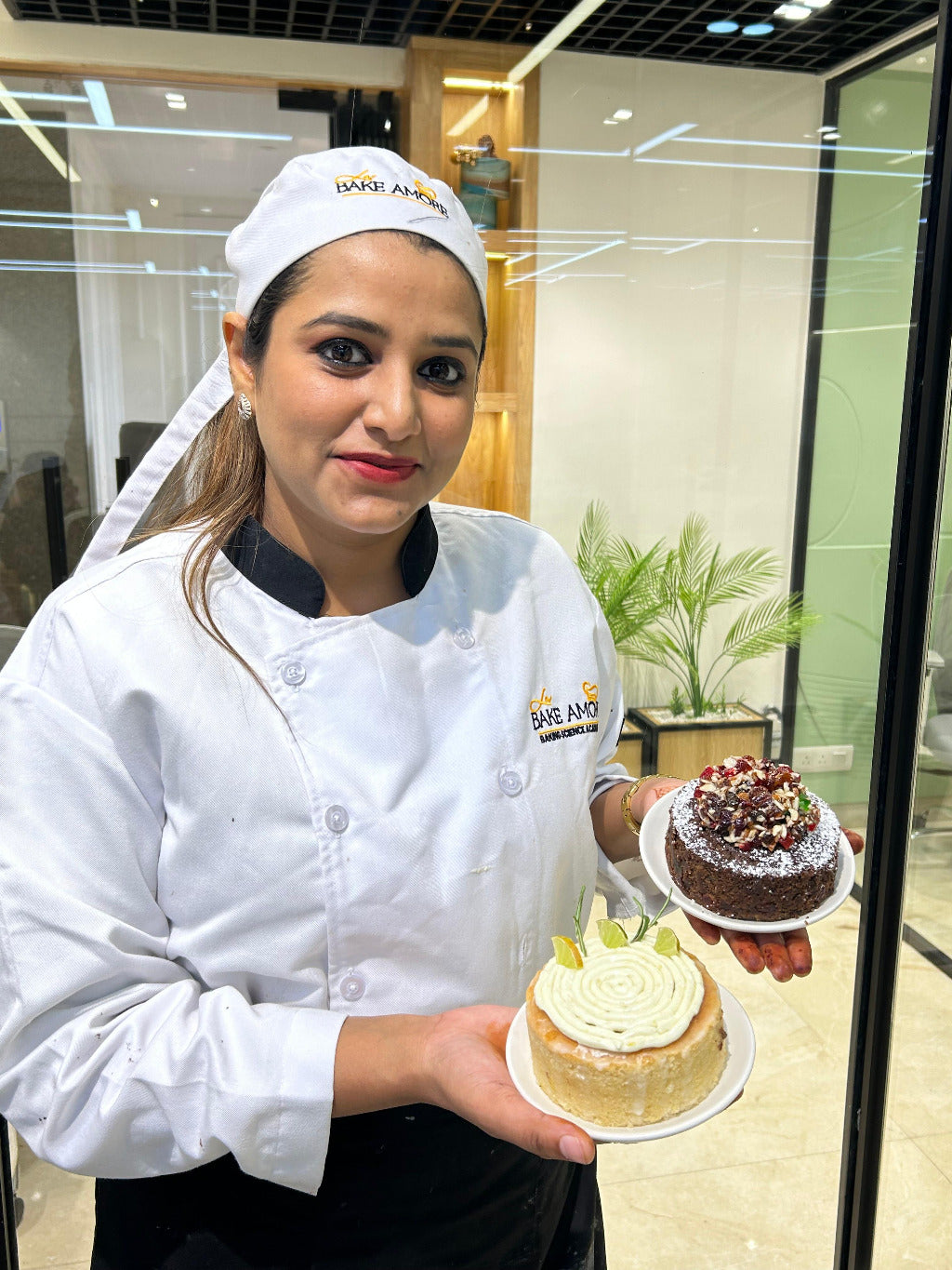 A person in a chef's outfit holding two baked goods, likely cupcakes or muffins, with a focus on presentation.
